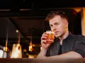Mężczyzna sączy orzeźwiający whisky sour, delektując się smakiem w nastrojowym barze.