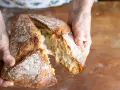 Ręce rozrywają świeży, chrupiący bochenek. Zastanawiasz się, jakie mąki na chleb bezglutenowy wybrać, by uzyskać taki efekt?