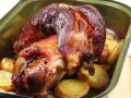 Zapieczona golonka z ziemniakami w naczyniu. Idealny sposób, jak zapeklować golonkę, by była soczysta i aromatyczna.