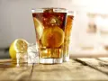 Dwa orzeźwiające drinki Long Island Iced Tea z plasterkami cytryny i lodem na drewnianym blacie.
