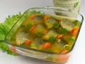 Gotowy przepis na rybę w galarecie: kawałki ryby z marchewką i natką pietruszki w bulionie, podane w szklanym naczyniu.