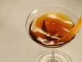 Elegancki Rob Roy cocktail w kieliszku, ozdobiony skórką pomarańczy.