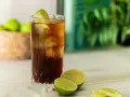 Orzeźwiający Cuba Libre z lodem i limonką, gotowy do świętowania.