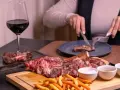 Idealne wino do dziczyzny? Czerwone, pełne, jak to w kieliszku obok soczystego steka i frytek. Ktoś kroi kolejny kawałek.
