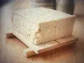 Kostka białego tofu, zrobionego z soi, na drewnianej podstawce.