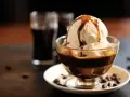 Lody waniliowe z syropem karmelowym w pucharku, obok szklaneczki z ciemnym napojem. Idealne połączenie, gdy zastanawiasz się, **Baileys z czym pić**.
