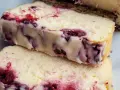 Dwa kawałki kremowego sernika z wiśniami, z widocznymi kawałkami owoców i ciemnym spodem.