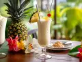 Dwa orzeźwiające drinki, które idealnie oddają, co to jest pina colada: kremowe, z ananasem i wisienką, otoczone świeżymi owocami i kwiatami.