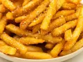Złociste, chrupiące frytki z parmezanem, posypane ziołami, kuszą swoim aromatem.