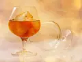 Kieliszek brandy z lodem, obok pusty, zapraszają do degustacji. Oto jak pić brandy, by docenić jej smak.