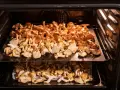 Suszenie grzybów w piekarniku. Na dwóch poziomach blachy ułożone są pokrojone kurki, które powoli tracą wilgoć.