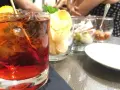 Orzeźwiający drink z rumem, lodem i cytryną, idealny do delektowania się w letni wieczór. Obok przekąski i chipsy.