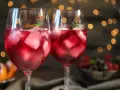 Dwa orzeźwiające drinki z prosecco i sprite, pełne lodu i listków mięty, na tle migoczących światełek.