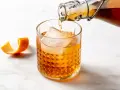 Amaretto co to? Bursztynowy likier migdałowy nalewany do szklanki z lodem, ozdobionej skórką pomarańczy.