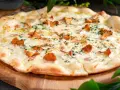 Pyszna pizza z kurkami, roztopionym serem i ziołami, podana na drewnianej desce.