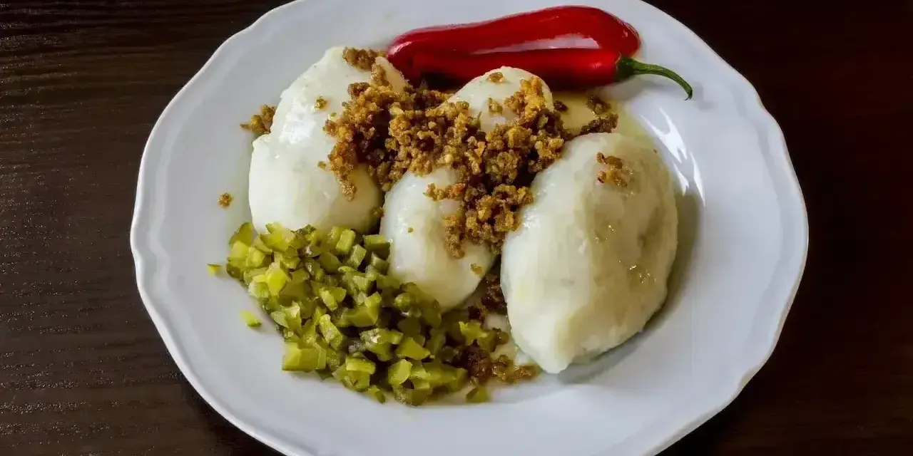 Trzy sycące kartacze z mięsem, posypane skwarkami, z dodatkiem ogórka kiszonego i ostrej papryczki.