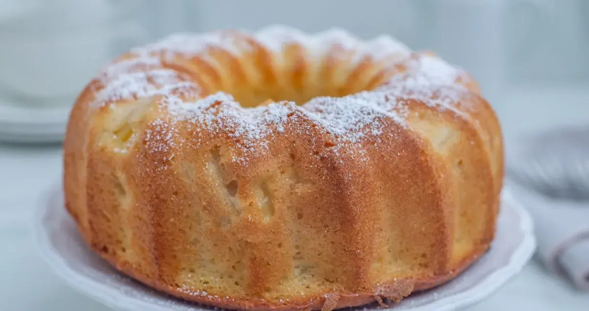 Najlepsza babka cytrynowa wilgotna na oleju, oprószona cukrem pudrem, prezentuje się apetycznie na białej paterze.