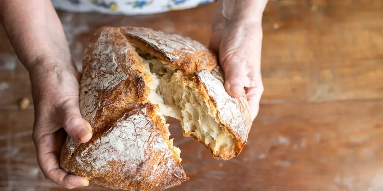 Ręce rozrywają świeży, chrupiący bochenek. Zastanawiasz się, jakie mąki na chleb bezglutenowy wybrać, by uzyskać taki efekt?