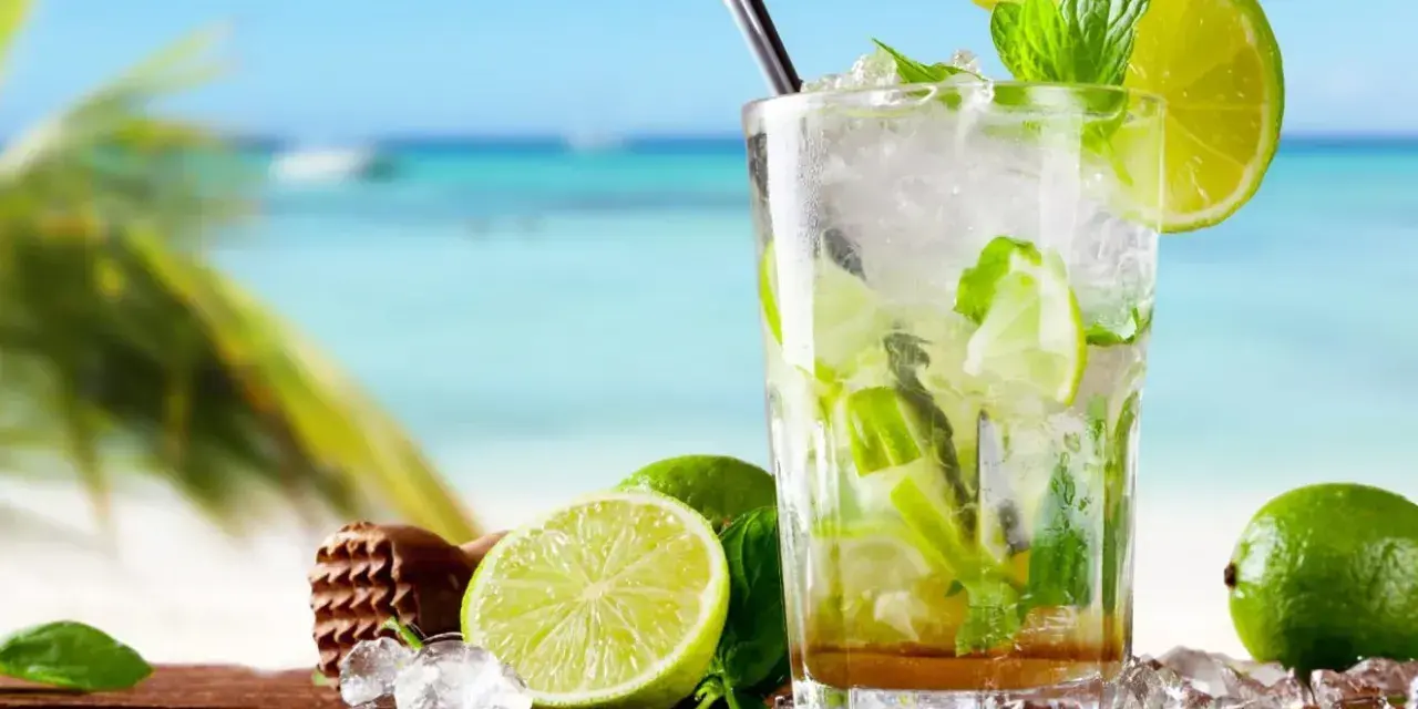 Orzeźwiający koktajl mojito z limonką i miętą na tle plaży. Idealny przepis na lato.