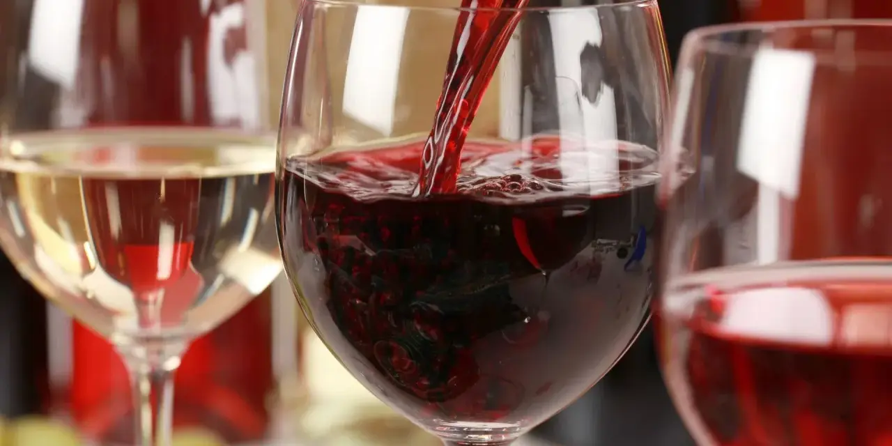 Czerwone wino leje się do kieliszka, obok stoi kieliszek białego wina. To może być najdroższe wino na świecie.