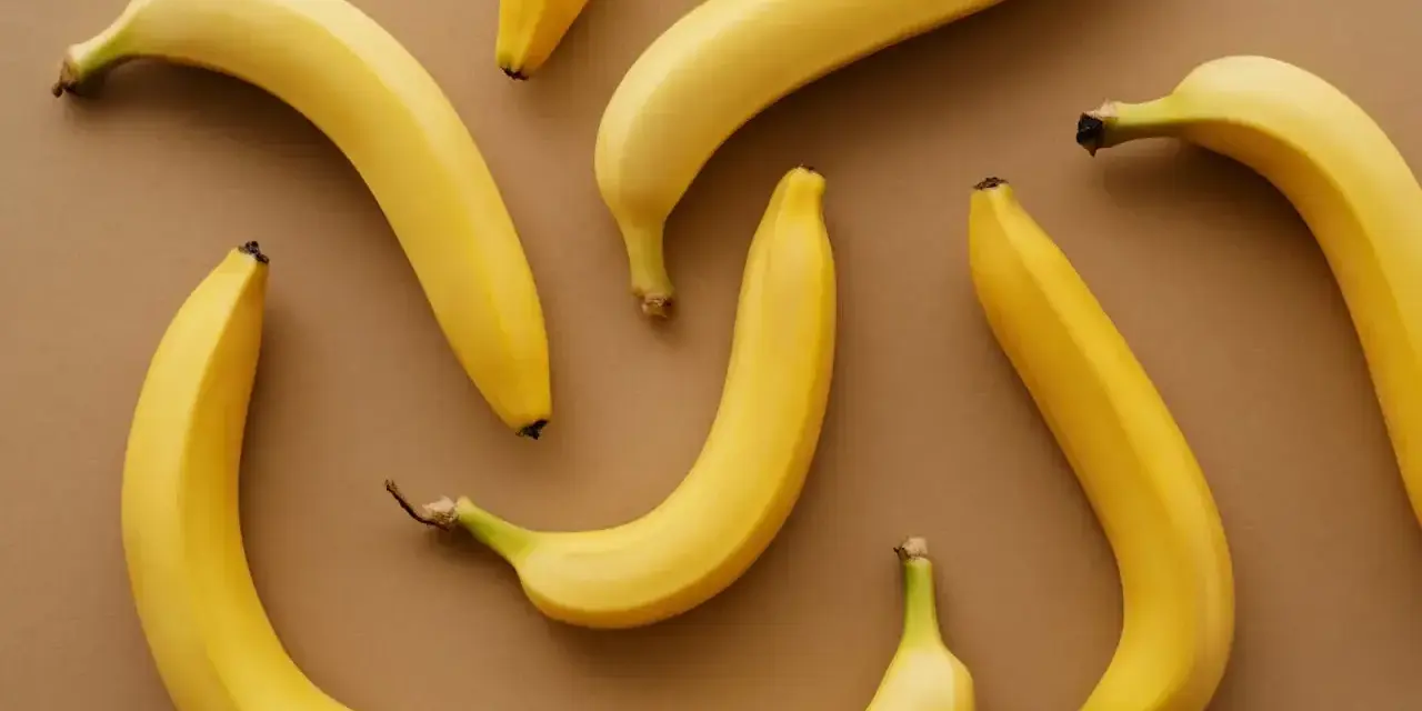 Kilka żółtych bananów ułożonych na brązowym tle. Czy banany można trzymać w lodówce?
