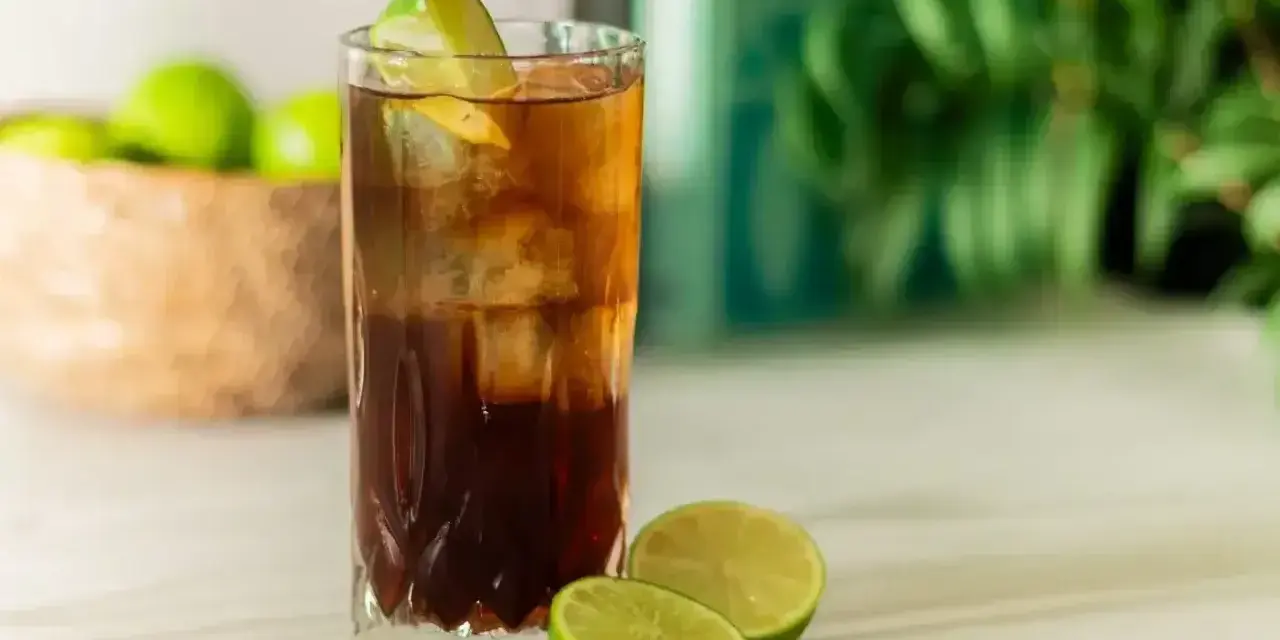 Orzeźwiający Cuba Libre z lodem i limonką, gotowy do świętowania.