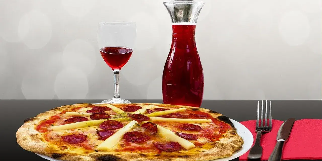 Pizza z kiełbasą i szparagami, kieliszek czerwonego wina i karafka. Idealne połączenie, zastanawiasz się, jakie wino do pizzy?