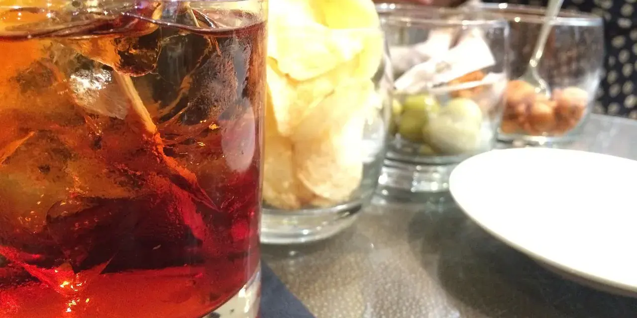 Orzeźwiający drink z lodem i cytryną, obok przekąski i inne likiery do drinków.