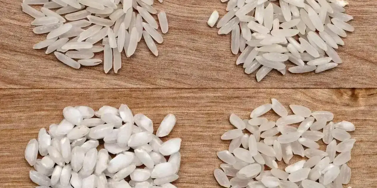 Cztery rodzaje ryżu, w tym ryż do risotto, ułożone na drewnianym tle.