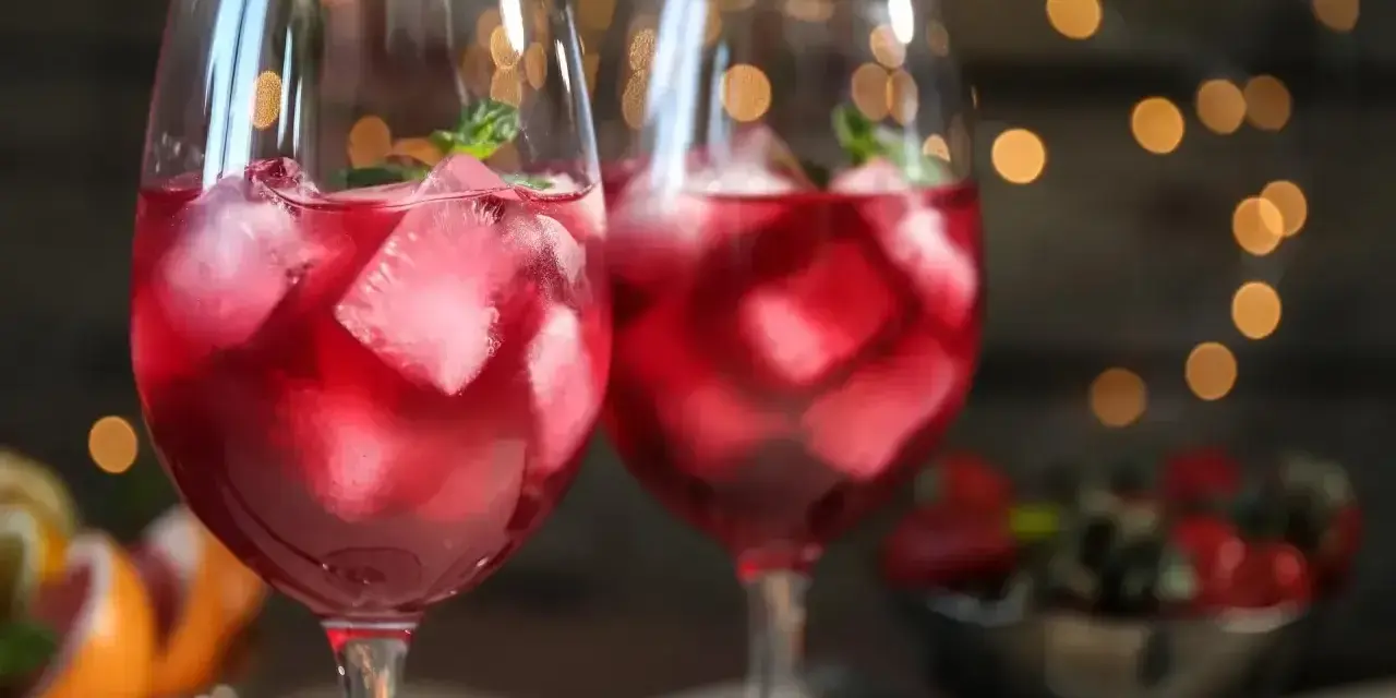 Dwa orzeźwiające drinki z prosecco i sprite, pełne lodu i listków mięty, na tle migoczących światełek.