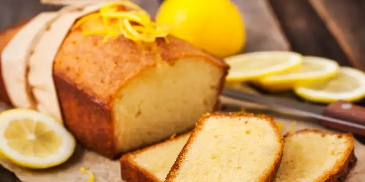 Wilgotna babka piaskowa z cytryną, ozdobiona skórką, podana z plasterkami cytryny.