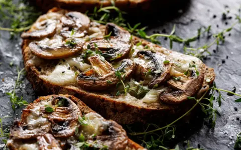 Pyszna zapiekanka z pieczarkami na chrupiącym pieczywie, posypana świeżym tymiankiem i solą.