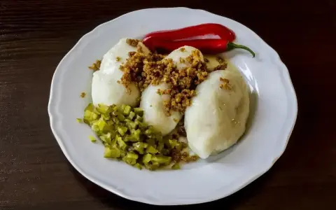 Trzy sycące kartacze z mięsem, posypane skwarkami, z dodatkiem ogórka kiszonego i ostrej papryczki.