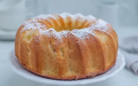 Najlepsza babka cytrynowa wilgotna na oleju, oprószona cukrem pudrem, prezentuje się apetycznie na białej paterze.