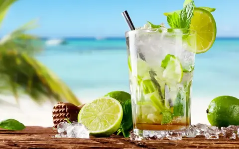Orzeźwiający koktajl mojito z limonką i miętą na tle plaży. Idealny przepis na lato.