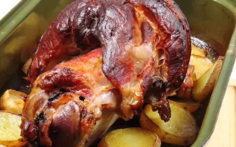 Zapieczona golonka z ziemniakami w naczyniu. Idealny sposób, jak zapeklować golonkę, by była soczysta i aromatyczna.