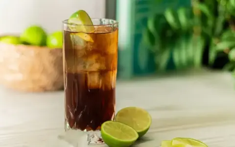 Orzeźwiający Cuba Libre z lodem i limonką, gotowy do świętowania.
