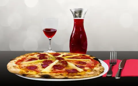 Pizza z kiełbasą i szparagami, kieliszek czerwonego wina i karafka. Idealne połączenie, zastanawiasz się, jakie wino do pizzy?