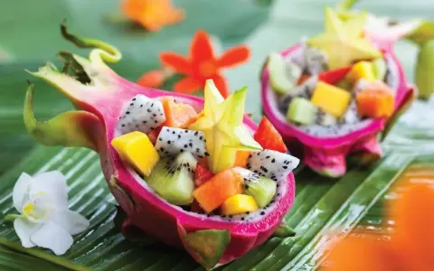 Smoczy owoc w formie miseczki wypełnionej egzotycznymi owocami: kiwi, mango, papają i karambolą.