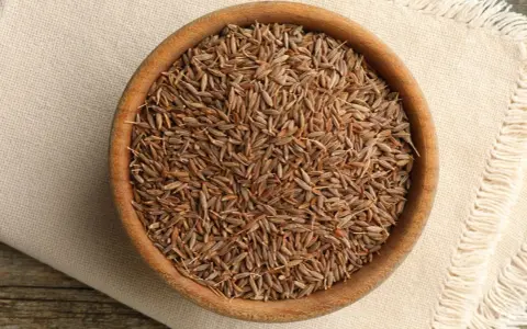 Drewniana miska pełna nasion kminu, znanego też jako kumin. Aromatyczna przyprawa gotowa do użycia.