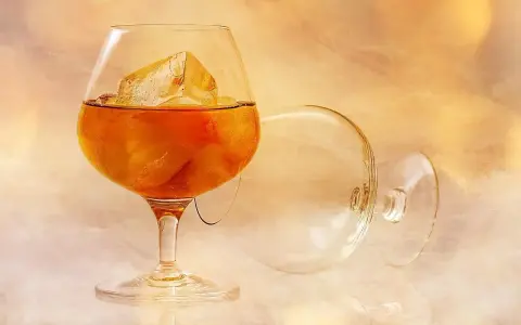 Kieliszek brandy z lodem, obok pusty, zapraszają do degustacji. Oto jak pić brandy, by docenić jej smak.