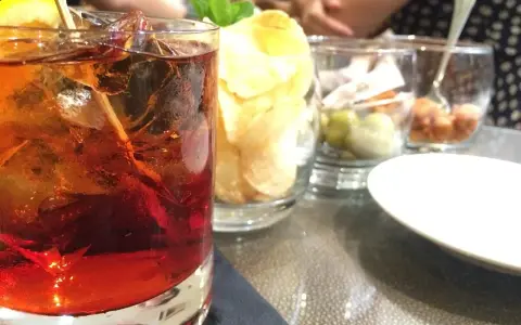 Orzeźwiający drink z rumem, lodem i cytryną, idealny do delektowania się w letni wieczór. Obok przekąski i chipsy.