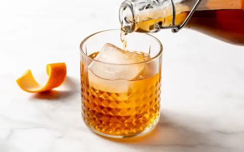 Amaretto co to? Bursztynowy likier migdałowy nalewany do szklanki z lodem, ozdobionej skórką pomarańczy.