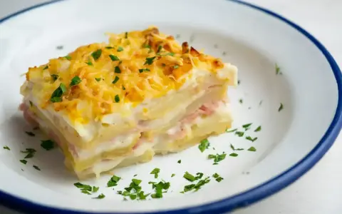 Pyszna warstwowa zapiekanka ziemniaczana z szynką i serem, idealna na obiad. Oto prosty lasagne przepis!