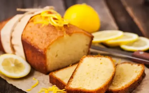 Wilgotna babka piaskowa z cytryną, ozdobiona skórką, podana z plasterkami cytryny.