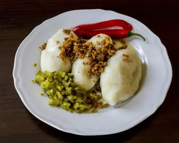 Trzy sycące kartacze z mięsem, posypane skwarkami, z dodatkiem ogórka kiszonego i ostrej papryczki.