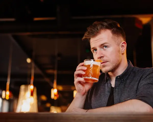 Mężczyzna sączy orzeźwiający whisky sour, delektując się smakiem w nastrojowym barze.