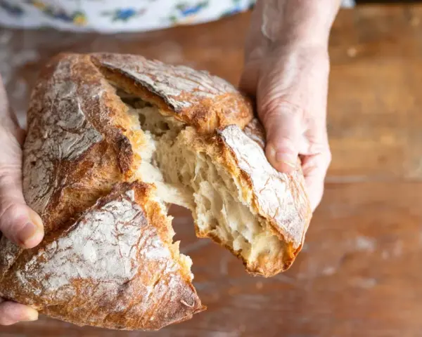 Ręce rozrywają świeży, chrupiący bochenek. Zastanawiasz się, jakie mąki na chleb bezglutenowy wybrać, by uzyskać taki efekt?