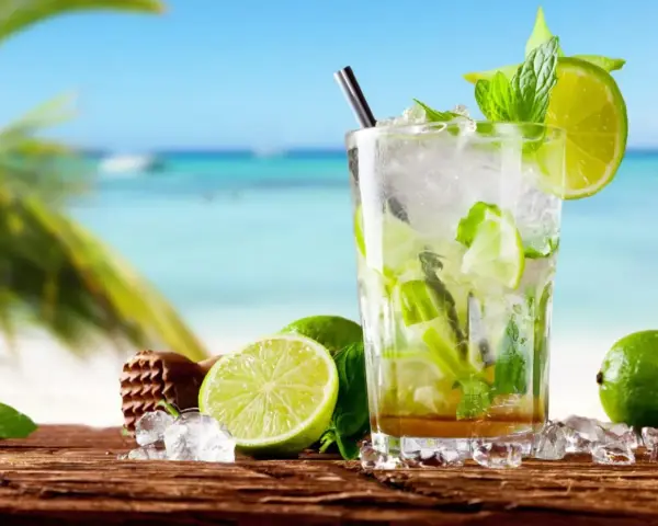 Orzeźwiający koktajl mojito z limonką i miętą na tle plaży. Idealny przepis na lato.