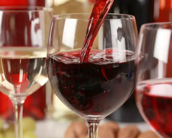 Czerwone wino leje się do kieliszka, obok stoi kieliszek białego wina. To może być najdroższe wino na świecie.
